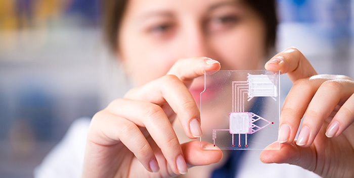 Female researcher showing a lab-on-a-chip device