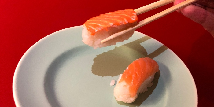 Photo: Printed vegi salmon to the left held with chopstick and real salmon to the right.